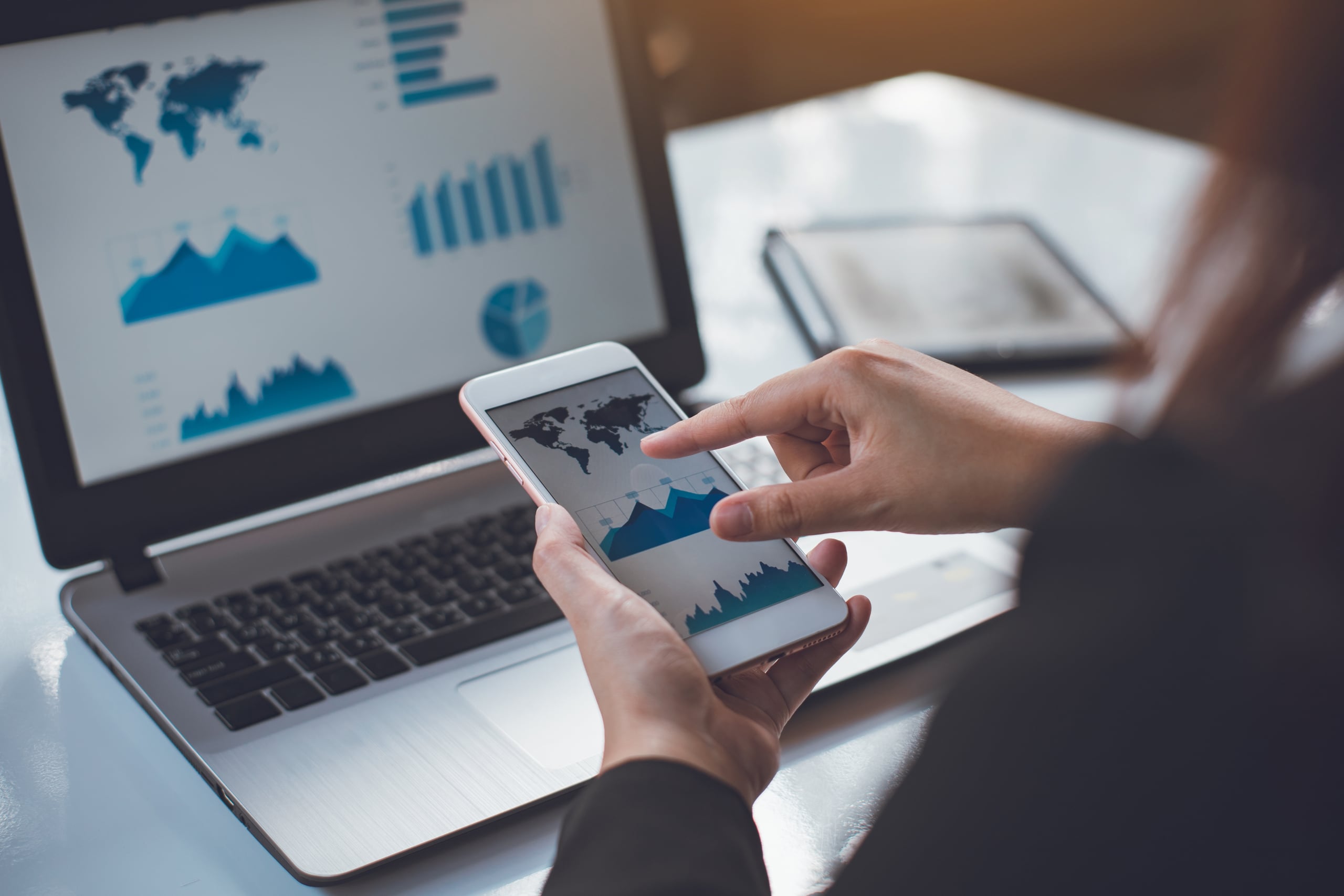 Hands analyzing charts on a tablet with growth dashboards